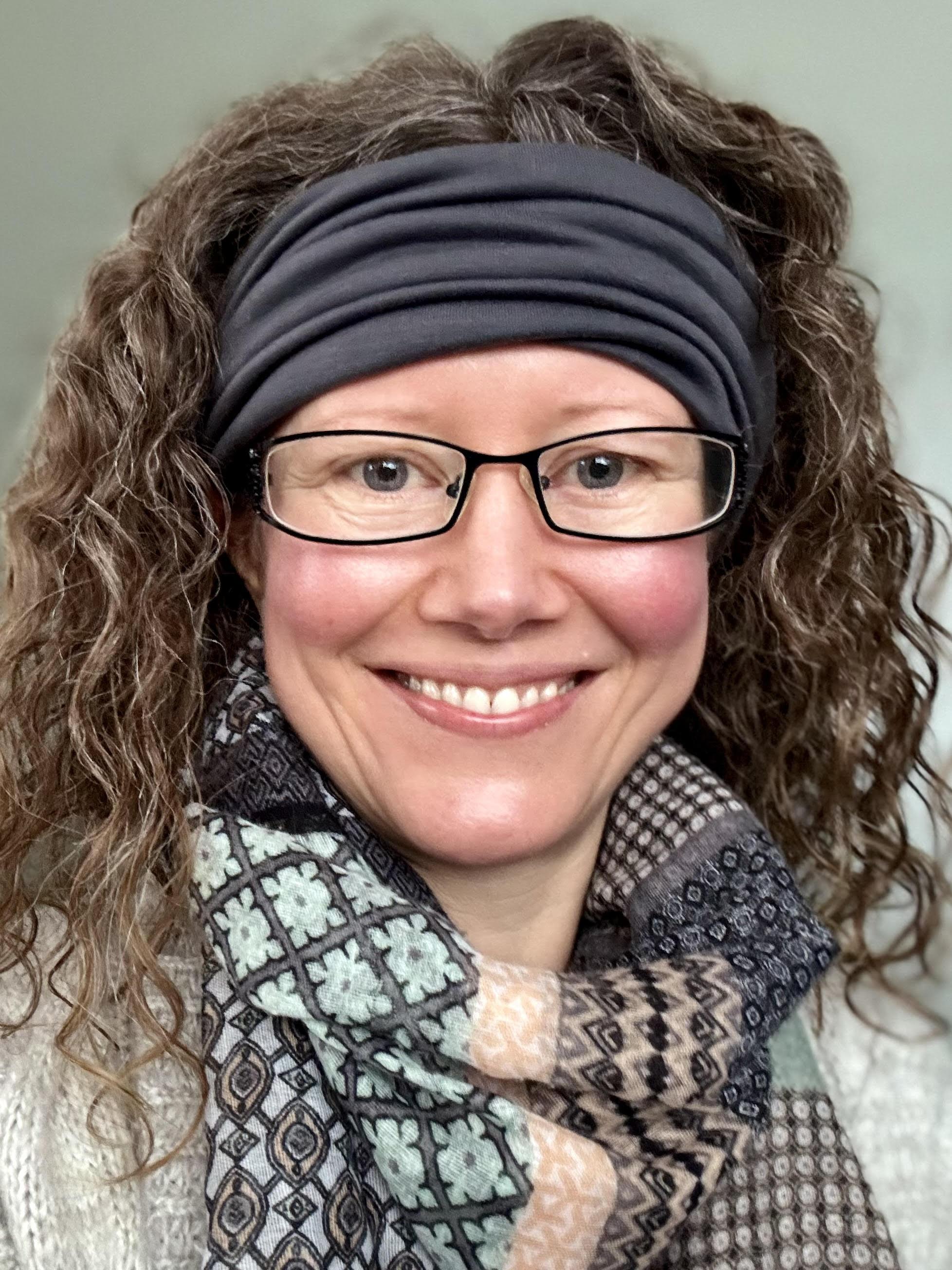 Melanie Counsellor head shot. Glasses, curly hair in a hairband