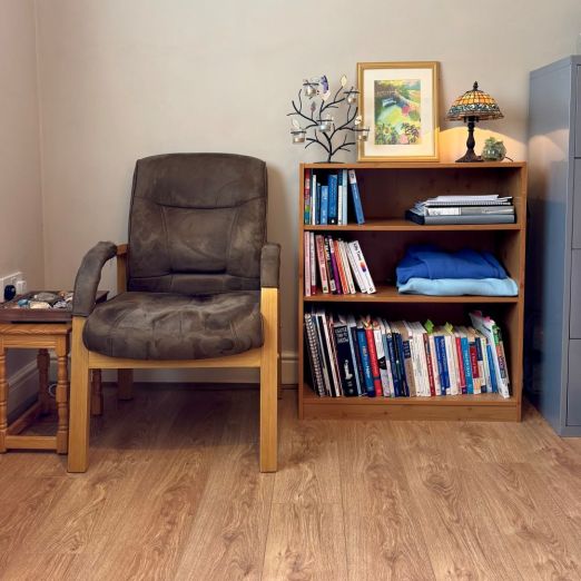 Therapy room showing chair book case with counselling books